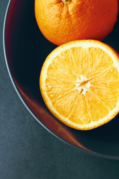 Fresh juicy oranges in black bowl healthy diet and nutrition