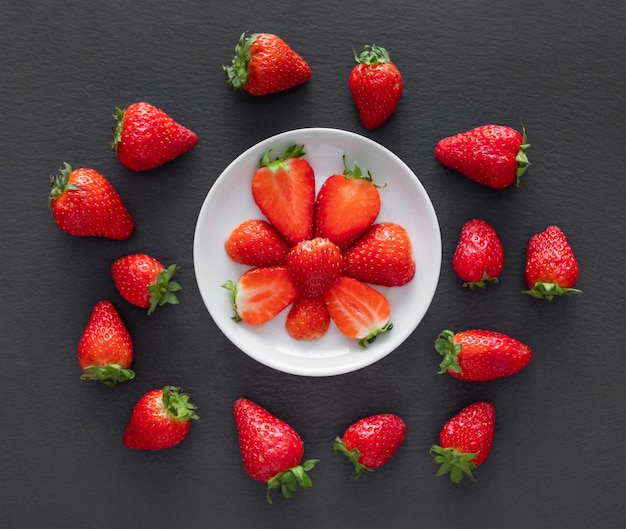 Fresh juicy sliced and whole strawberries on a gray background