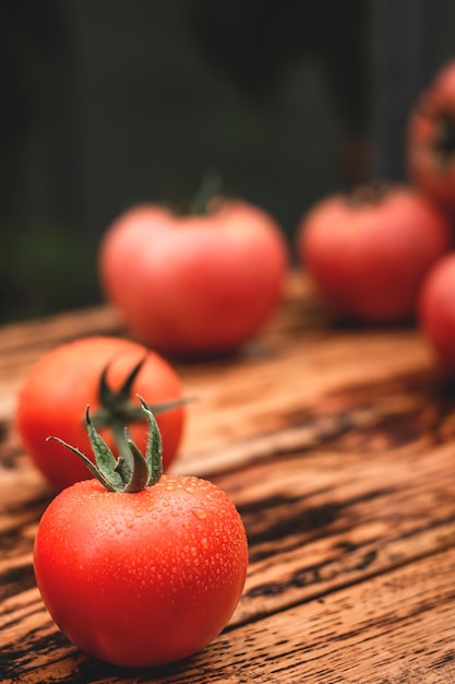 Fresh juicy tomatoes covered with water drops on a wooden table