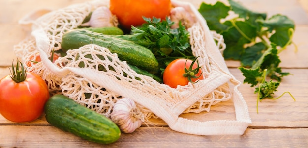 Fresh juicy vegetables products in a reusable shopping bag a string bag made of recycled materials on a wooden table in the garden Vegetarianism No plastic Ecofriendly lifestyle