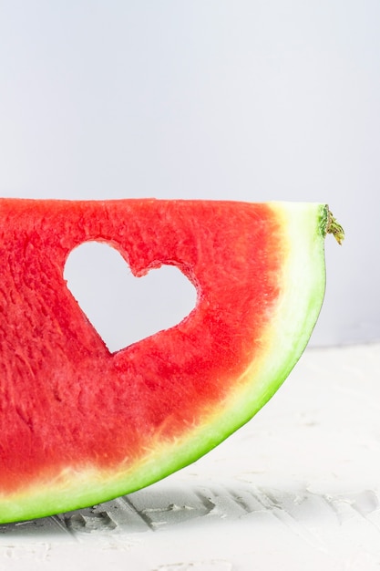 Fresh juicy watermelon slice with heart shape hole on white background. Valentines, love, summer concept with copy space