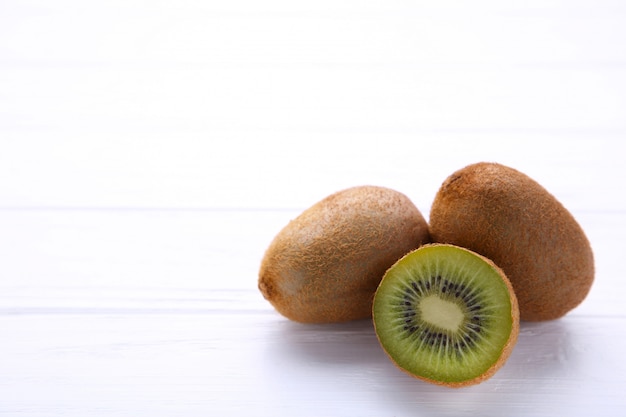 Fresh kiwi fruit and half of kiwi on white wooden background