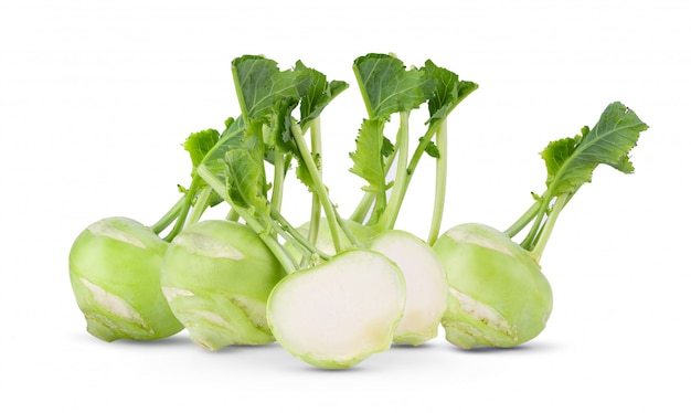 Fresh kohlrabi with green leaves on white wall. 