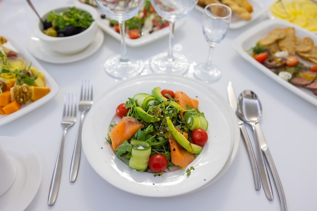 Fresh lamb lettuce salad with avocado, cucumber, salmon, cherry tomatoes. Dressing with honey, dijon mustard, olive oil and lemon juice, topped with chia seeds. Prepared by chef.