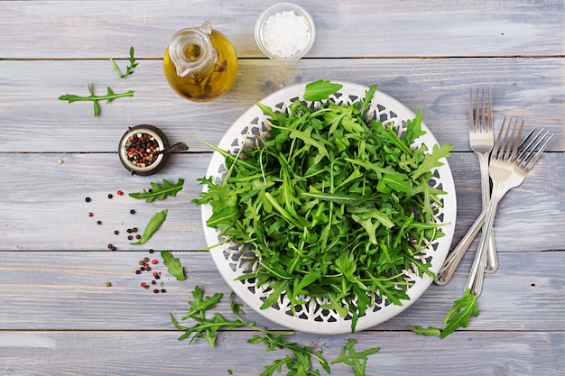 Fresh leaves of arugula in a bowl on a light wooden background. 