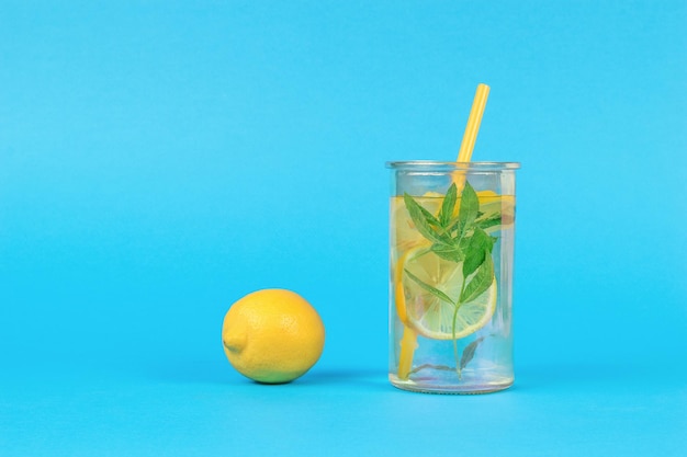 Fresh lemon and a glass of water with mint and lemon on a blue background