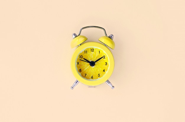 Fresh lemon slice in small yellow alarm clock