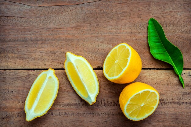 Fresh lemons and  lemons leaves on rustic wooden background.