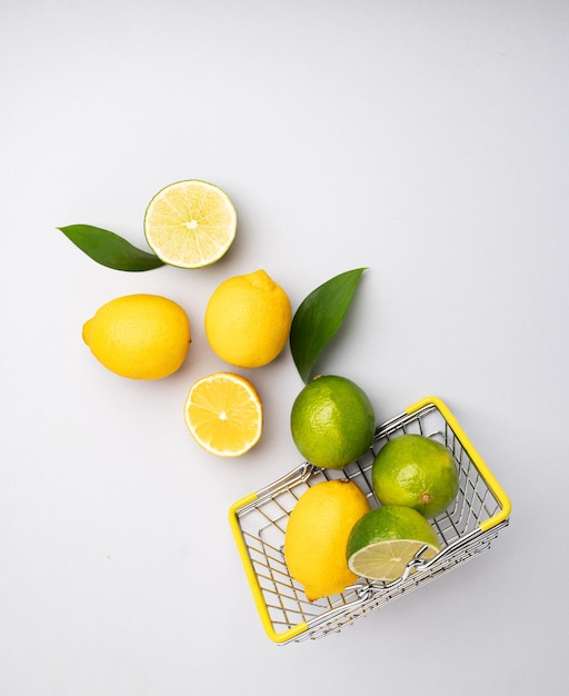 Fresh lemons and limes fall out of a supermarket basket on a blue background Citrus fruit concept for freshly squeezed lemonade Top view and copy space