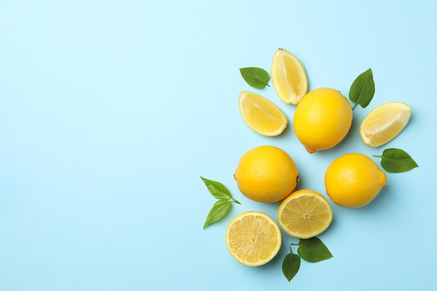 Fresh lemons with leaves on blue surface. Ripe fruit