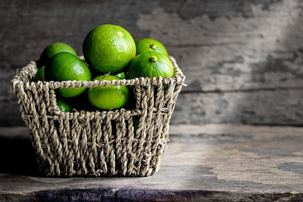 Fresh limes in the basket on a wooden background