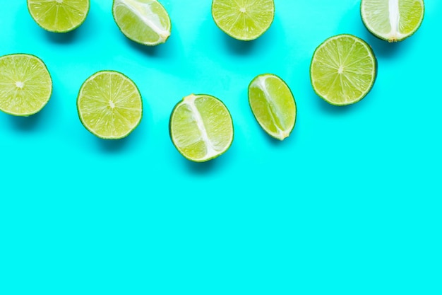 Photo fresh limes on blue background top view