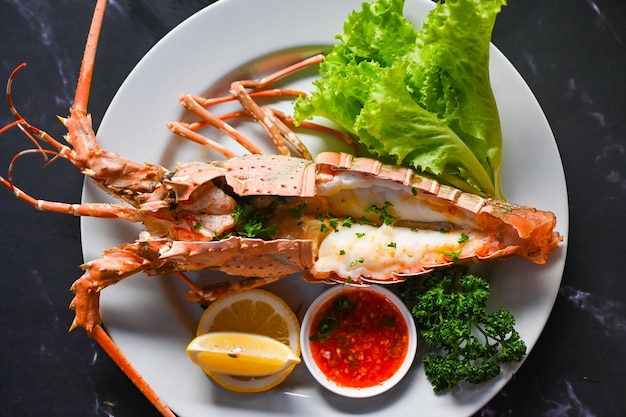 Fresh lobster or rock lobster seafood with herb and spices lemon coriander parsley lettuce salad spiny lobster food on plate lobster for cooking food and seafood sauce