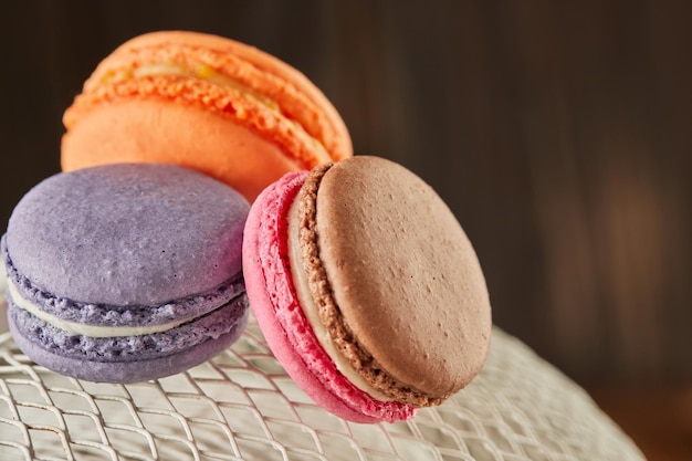 Fresh macarons of different colors and flavors on a white metal mesh