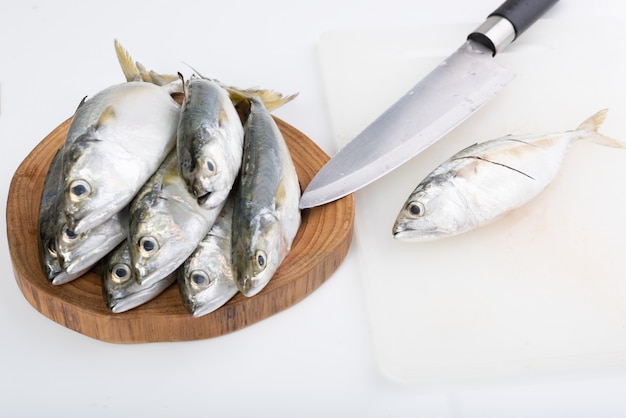 Fresh Mackerel fish and knife on wooden chopping board on white