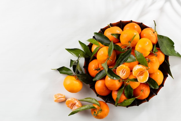 Fresh mandarin oranges fruit with leaves in wooden box, top view.