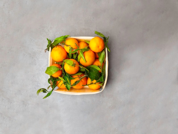 Fresh mandarins in wooden box isolated on stone table