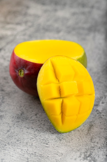 Fresh mango fruit with slices placed on stone background. 