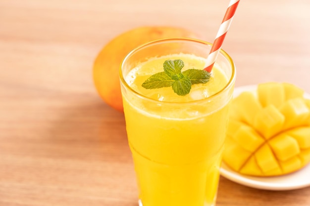 Fresh mango juice with beautiful chopped pulp flesh on bright wooden table background Tropical fruit drink design concept Close up copy space