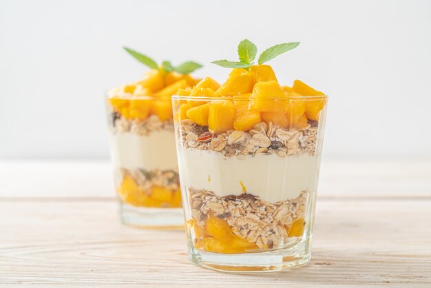 fresh mango yogurt with granola in glass - healthy food style