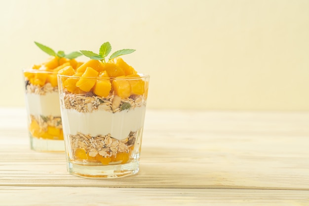 fresh mango yogurt with granola in glass - healthy food style