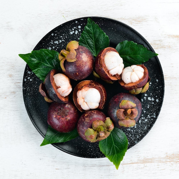 Photo fresh mangosteen in the dish tropical fruits top view free space for text