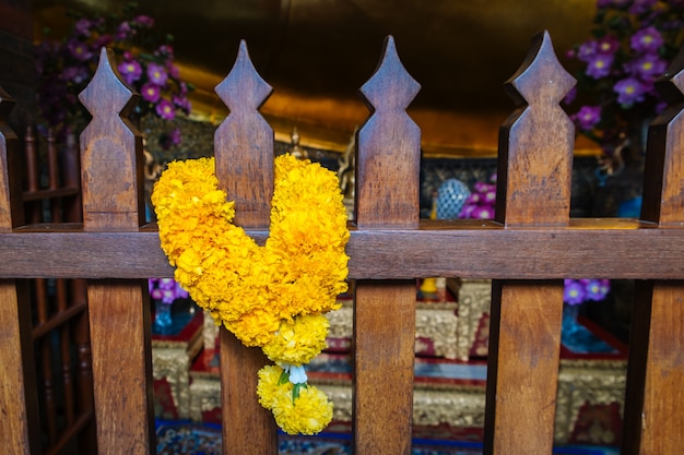 A fresh marigold garland hanging on the wooden fence in Wat Pho temple, Bangkok, Thailand.