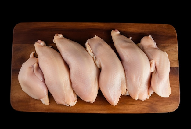 Fresh meat chicken breasts lying on a kitchen board and a black background