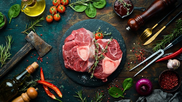 Fresh meat Ossobuko steak on the bone with rosemary and spices On a black stone background Top view