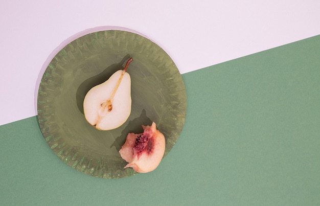 Fresh minimalist scene Organic pears and peach on green plate and bicolor paper background