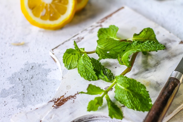 Fresh mint leaves and lemon on a cutting board with a knife