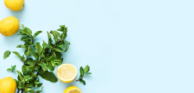 Fresh mint and lemons for making lemonade on a blue table.