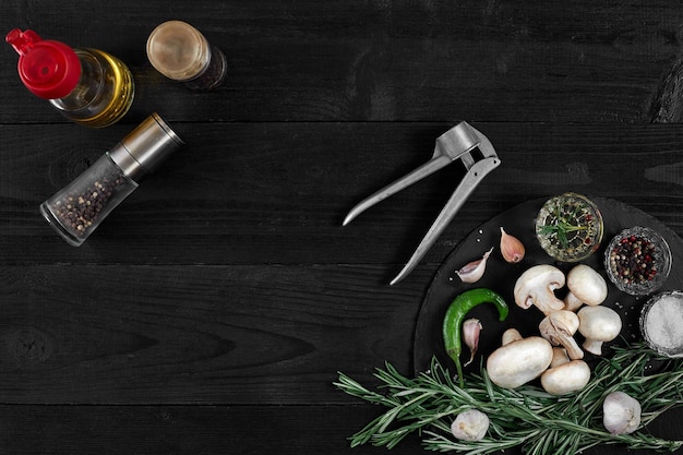 Fresh mushrooms with spices and herbs on a black board on a black wooden background Top view with copy space Still life Flat lay