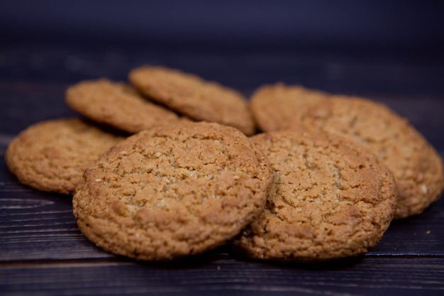 Fresh oatmeal cookies are laid out on a dark wooden background