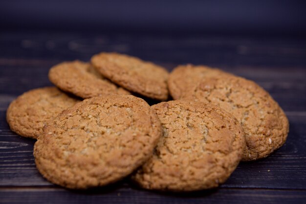 Fresh oatmeal cookies are laid out on a dark wooden background