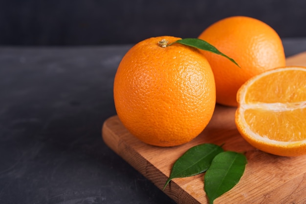 Fresh orange fruit with green leaves on wooden table