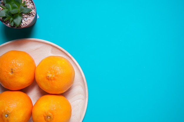 Fresh orange fruits and juice on blue table.