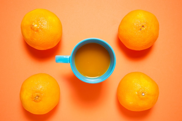 Fresh orange fruits and juice on orange table.