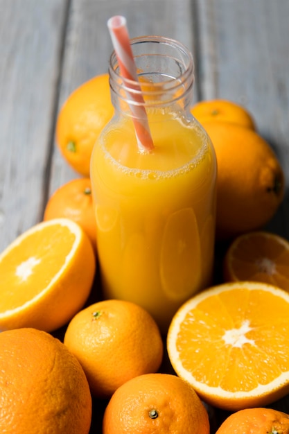 Fresh orange juice in a bottle with oranges on a rustic wooden background