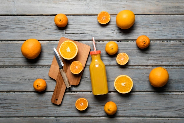 Fresh orange juice in a bottle with oranges on a rustic wooden background