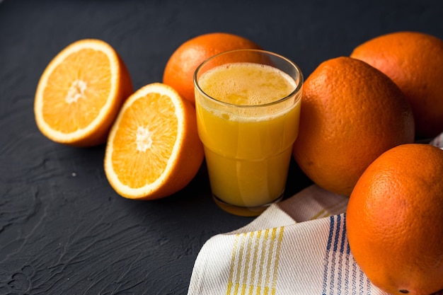 Fresh orange juice and fresh fruit oranges on a black table