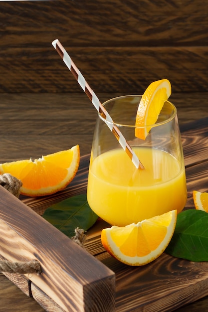 Fresh orange juice in glasses with cut oranges on wooden tray. Rustic still life with citrus fruits.