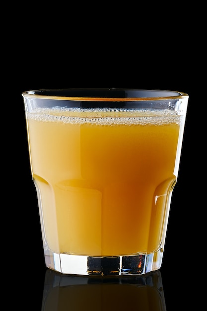 Fresh orange juice in rocks glass isolated on black surface