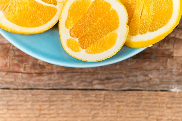 Fresh oranges cut in halves on a blue plate, extreme close up look, isolated on a wooden table, no people shown