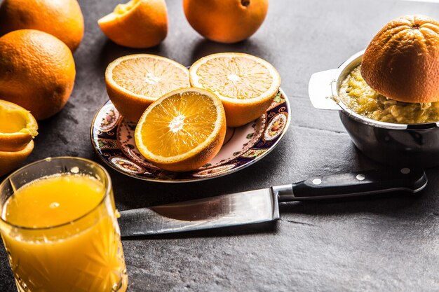 Fresh oranges juicer juice and tropical fruits on concrete board.