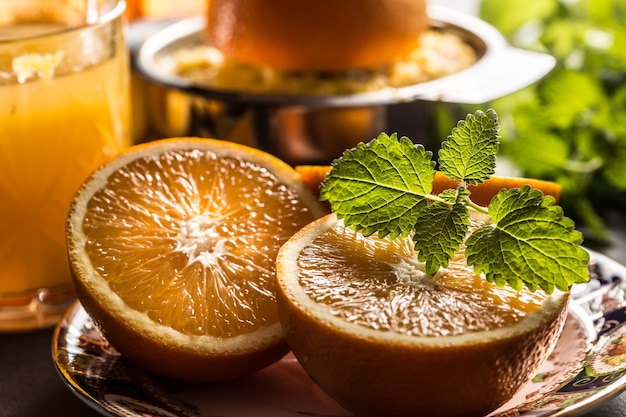 Fresh oranges juicer juice tropical fruits and herbs on concrete board.