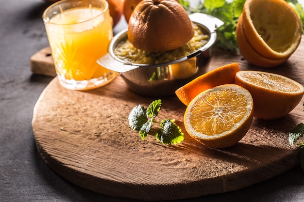 Fresh oranges juicer juice tropical fruits and herbs on concrete board.