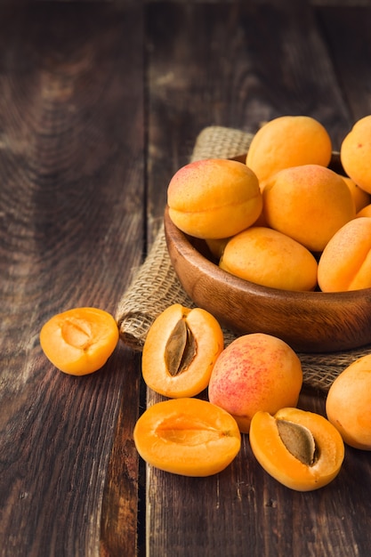 Fresh organic apricots in wooden bowl on rustic wooden