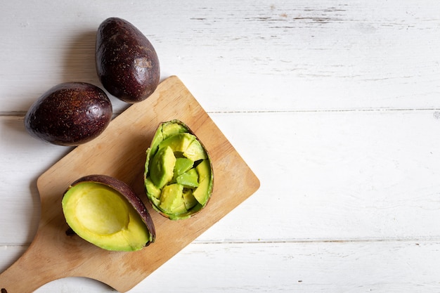 Fresh organic avocado sliced in half on white wooden table