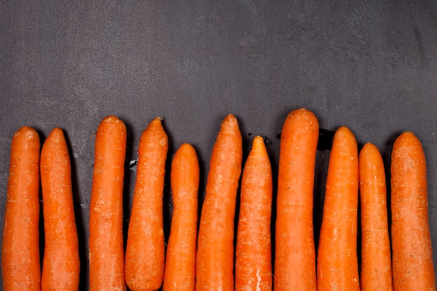 Fresh organic carrots on black background.